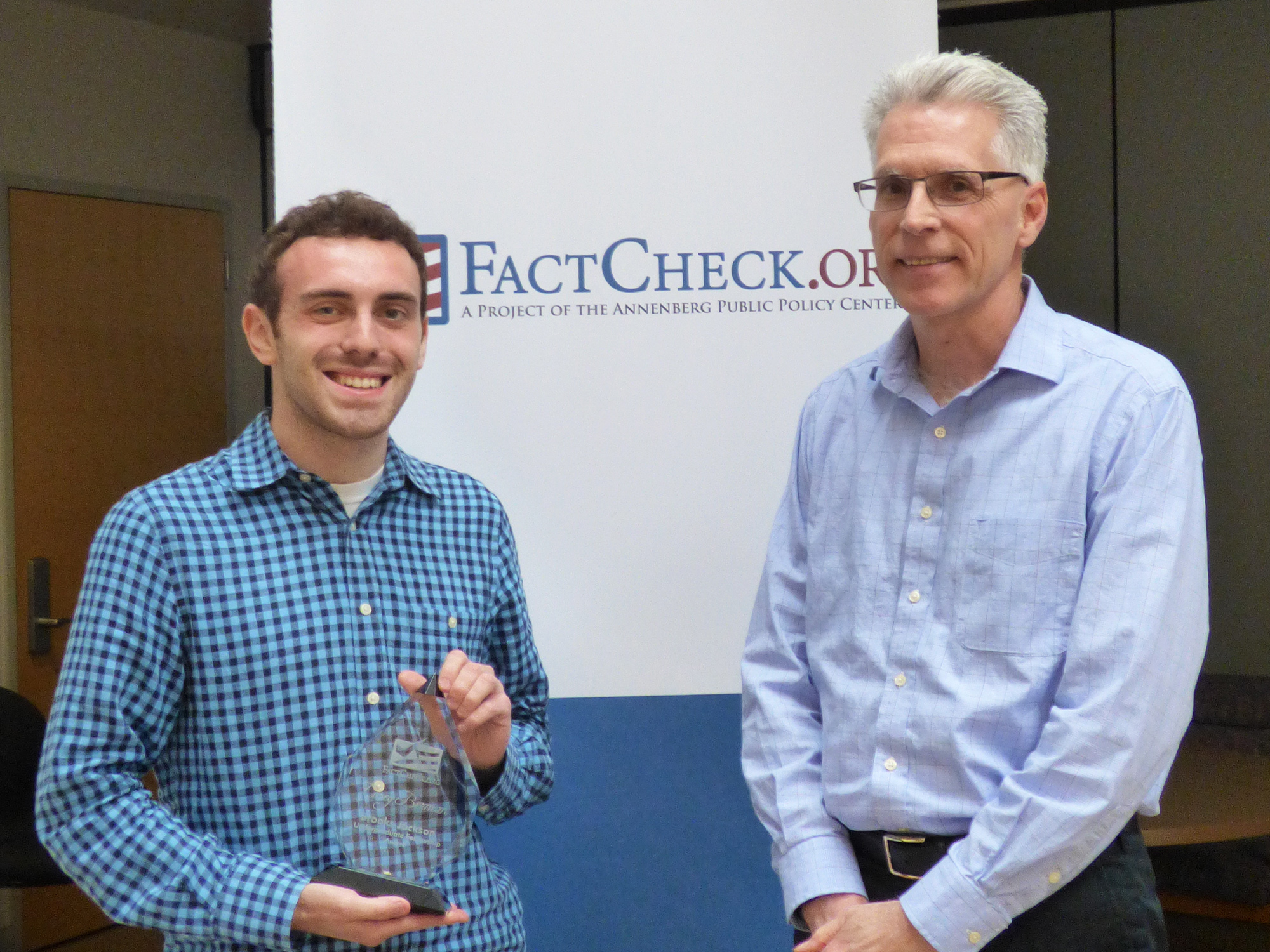 Corey Berman (left), holding the Brooks Jackson Undergraduate Fellowship Award, and FactCheck.org director Eugene Kiely.