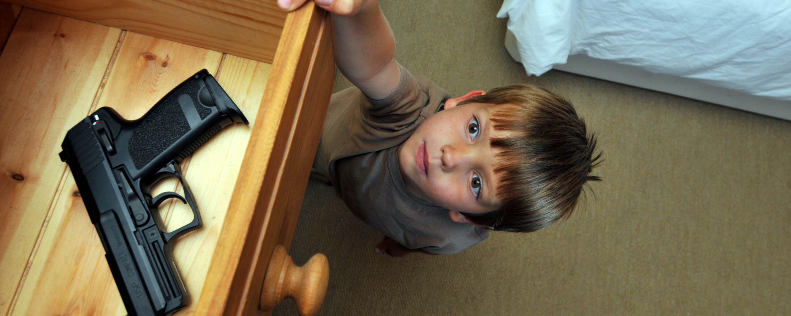 Photo of a child reaching into drawer in household with gun stored unlocked.