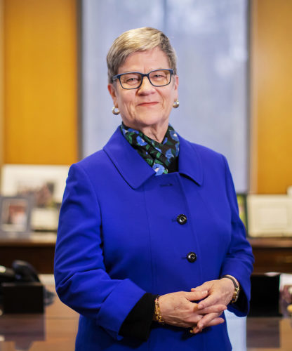 Photo of Kathleen Hall Jamieson, white woman with glasses and gray hair wearing a royal blue jacket.