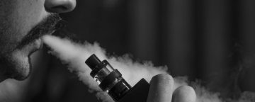 Black and white photo of a man smoking from a vape